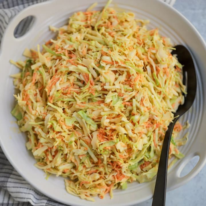 Coleslaw plated in white serving dish.